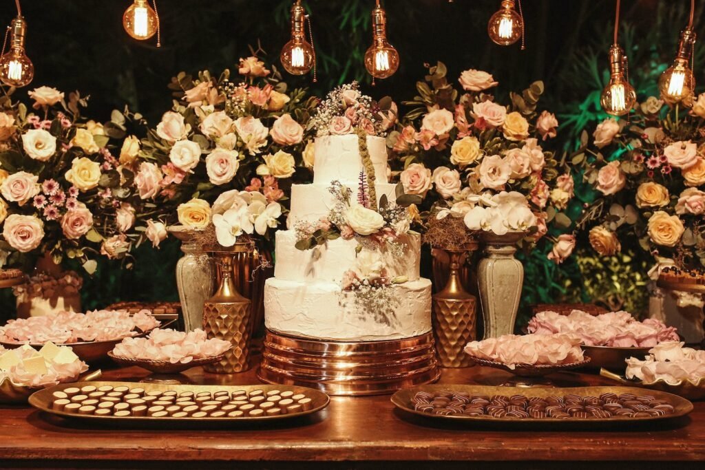Wedding Cake Surrounded by Vases with Beautiful Flowers on the Table